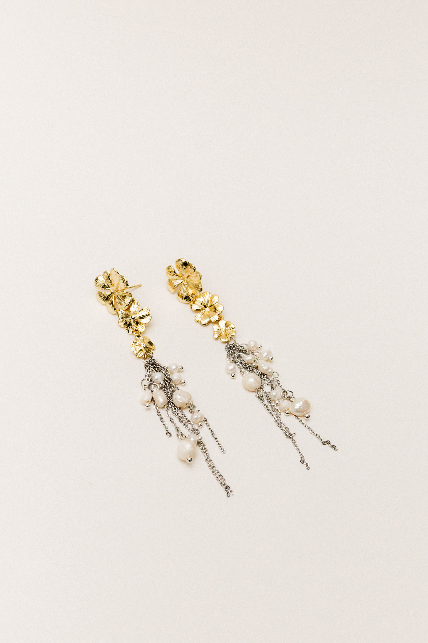 Pendientes Flora hechos a mano en Galicia con diseño floral en latón, cadenas de acero inoxidable y perlas de río.
